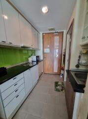 Modern kitchen with green backsplash, white cabinets, and wooden door