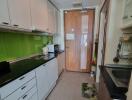 Modern kitchen with green backsplash, white cabinets, and wooden door