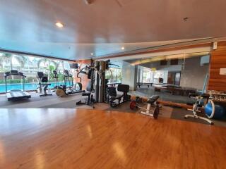 Modern gym with various exercise equipment and a view of the pool