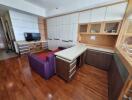 Modern living room with wooden flooring, built-in storage, and TV area