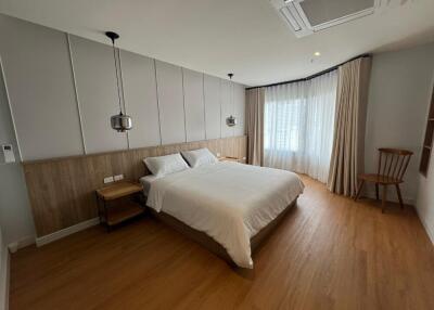 Modern bedroom with large bed, wooden flooring, and large windows