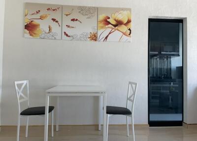Small dining area with white table and chairs, floral wall art, and partial view of kitchen