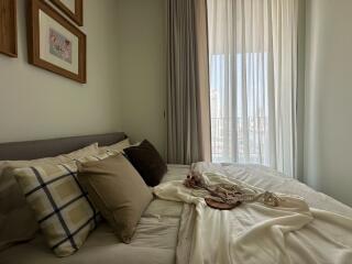 Cozy bedroom with decorative pillows and a large window with curtains