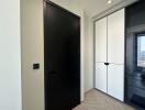 Hallway with black door and white storage cabinets