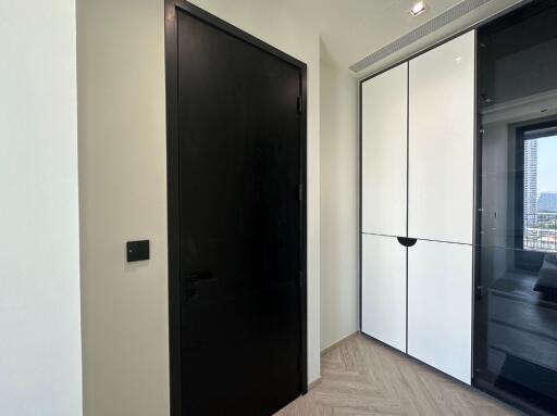 Hallway with black door and white storage cabinets