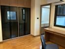 Bedroom with wooden floor, built-in wardrobe, and desk with chair