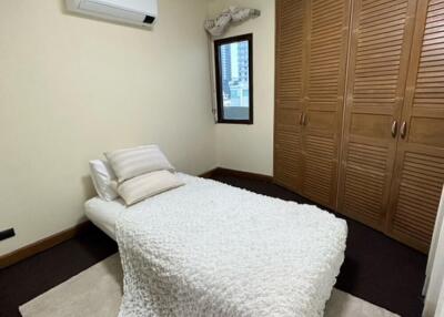 Cozy bedroom with a single bed, wooden wardrobe, and an air conditioner