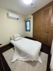 Cozy bedroom with a single bed, wooden wardrobe, and an air conditioner