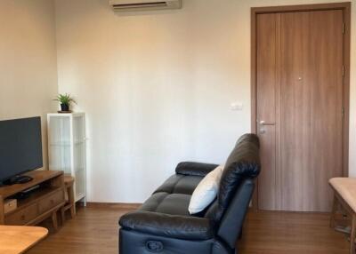 Living room with a leather sofa, TV setup, wooden floor, and air conditioning