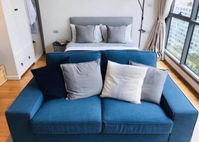 Modern bedroom with a blue couch and a large window