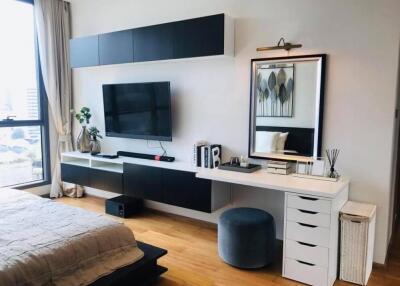 Modern bedroom with TV, wall-mounted shelves, and a work desk