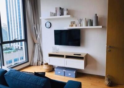 Modern living room with wall-mounted TV, shelves, and large window