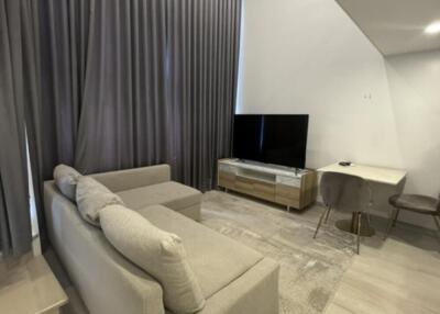 Modern living room with beige sofa, flat-screen TV, and tall curtains