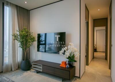 Modern living room with natural light, TV, and hallway