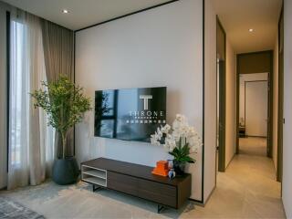 Modern living room with natural light, TV, and hallway