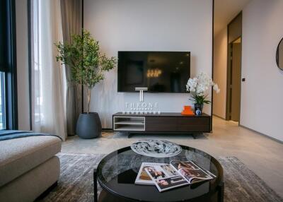 Modern living room with a large TV, plants, and a coffee table