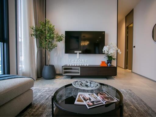 Modern living room with a large TV, plants, and a coffee table