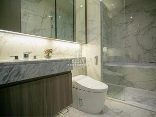 Modern bathroom with marble walls, large mirror, and glass-enclosed shower