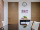 Dining area with wooden doors, wall clock, and framed pictures