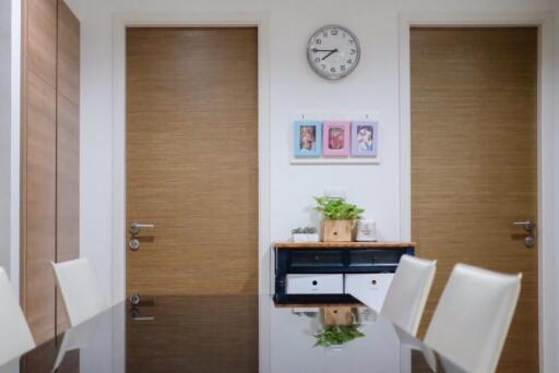 Dining area with wooden doors, wall clock, and framed pictures