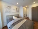 Modern bedroom with framed artworks, cozy bed, and wooden flooring