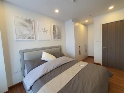 Modern bedroom with framed artworks, cozy bed, and wooden flooring