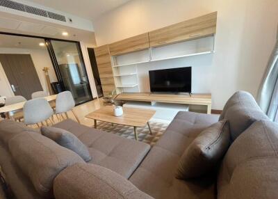 Modern living room with a sectional sofa, TV, wooden coffee table, and dining area