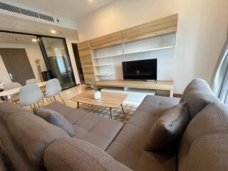 Modern living room with a sectional sofa, TV, wooden coffee table, and dining area