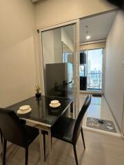 modern dining area with glass table and two chairs near glass sliding door to balcony