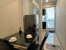 modern dining area with glass table and two chairs near glass sliding door to balcony