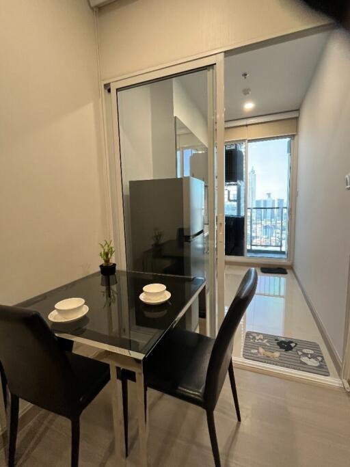 modern dining area with glass table and two chairs near glass sliding door to balcony