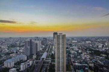 A high-rise residential building with a view of a city skyline at sunset