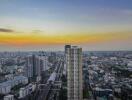 A high-rise residential building with a view of a city skyline at sunset