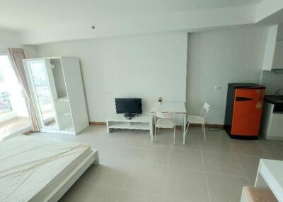 Studio apartment with bed, TV, dining area, small kitchen, and a balcony