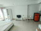 Studio apartment with bed, TV, dining area, small kitchen, and a balcony