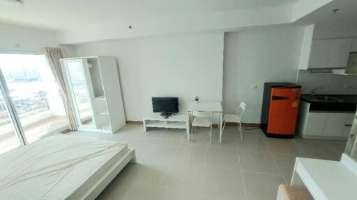 Studio apartment with bed, TV, dining area, small kitchen, and a balcony