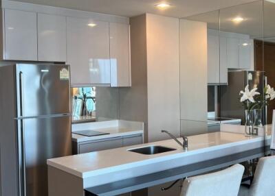 Modern kitchen with white cabinets, stainless steel refrigerator, and breakfast bar