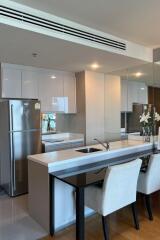 Modern kitchen with white cabinets, stainless steel refrigerator, and breakfast bar