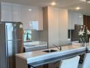 Modern kitchen with white cabinets, stainless steel refrigerator, and breakfast bar