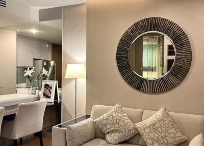 Modern living room with a sofa, decorative pillows, a lamp, and a large round mirror