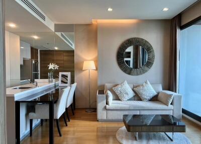 Modern living room with sofa, decorative mirror, coffee table, dining area, and floor lamp