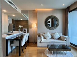 Modern living room with sofa, decorative mirror, coffee table, dining area, and floor lamp