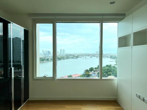 A bedroom with a large window offering a scenic river view