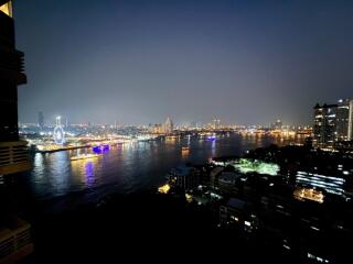 night view of an urban skyline with a river and ferris wheel