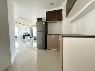 Modern kitchen with sleek cabinets and refrigerator, leading to open living space