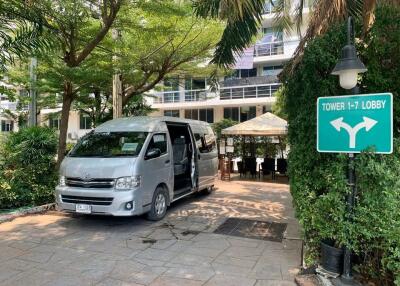 Entrance area with a van parked, greenery, and lobby direction sign