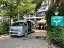 Entrance area with a van parked, greenery, and lobby direction sign