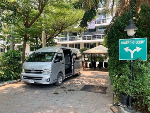 Entrance area with a van parked, greenery, and lobby direction sign