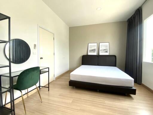 Modern bedroom with bed, wooden flooring, desk and chair