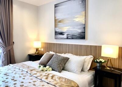 Cozy bedroom with bed, pillows, bedside tables, lamps, and wall art